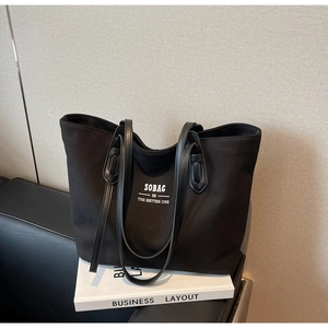 Close-up of black canvas tote bag with white lettering on a stylish prop book