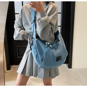 Mirror selfie showing the blue denim crossbody moon bag with adjustable strap and logo