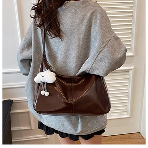 Brown leather tote bag featuring a glossy finish and a cute white cloud pendant