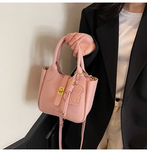 Detailed shot of pink pebble leather bag featuring bear charm and gold turn-lock closure