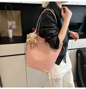 Detail der rosa geflochtenen Tragetasche mit Bärenanhänger an der Modelschulter