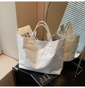 Dettaglio borsa tote bianca lucida con texture stropicciata e logo 'TOTE BAG' inciso