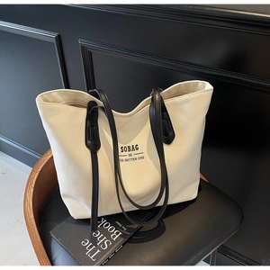 Detail of off-white canvas tote with black leather handles and SOBAG typography