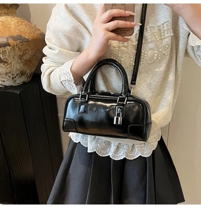 Close-up of shiny black faux leather Boston bag with silver metal lock and top handles