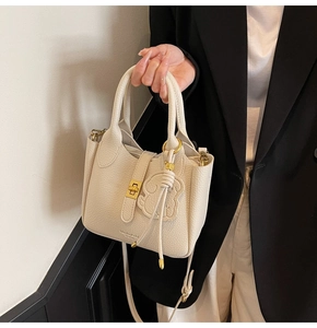 Detail of cream lychee leather bucket bag with gold clasp and brand logo detail