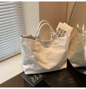 Dettaglio della borsa tote bianca con scritta a rilievo e ampi manici alla moda