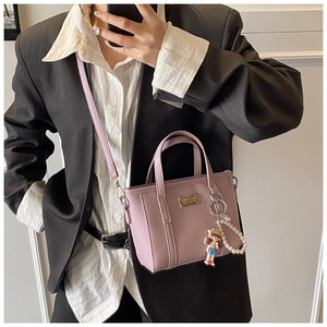 Detail of light purple lychee leather bucket bag with cute doll charm and pearl strap