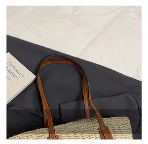Dettaglio dei manici in pelle marrone e trama intrecciata di una borsa tote in paglia