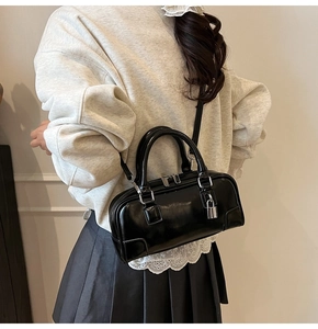 Detailed view of a black glossy Boston bag worn by a model to show its actual size and shine