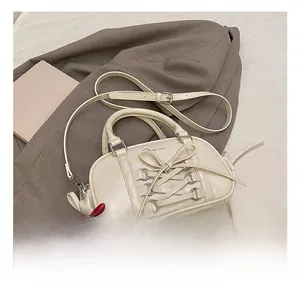 Close-up of cream Boston bag featuring lace-up bow details and silver hardware rings