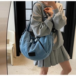 Adjustable wide shoulder strap detail on blue denim croissant bag with metal buckle