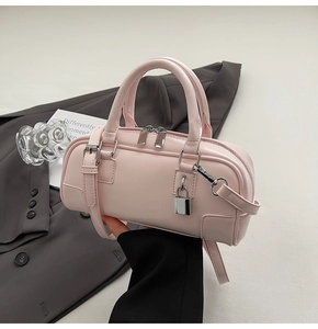 Detailed view of a pink mini Boston bag featuring silver lock and dual zipper design