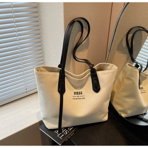 Detail of canvas tote bag showing black straps and SOBAG logo in soft natural light