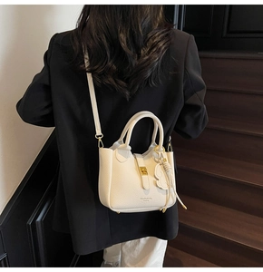 Detailed view of beige pebble leather bucket bag with cute elephant charm and gold hardware