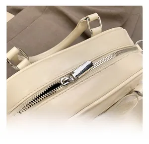 Close-up of premium cream faux leather top zipper and silver metal hardware on handbag