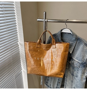 Dettaglio di una borsa tote marrone con trama carta stropicciata e finitura lucida