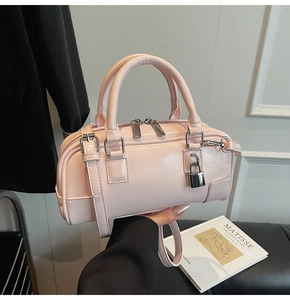 Close-up of light pink glossy leather Boston bag with silver hardware and top handles