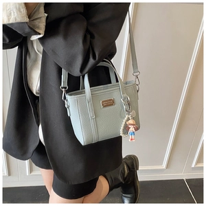 Detail of light blue lychee pattern bucket bag with pearl and cartoon girl charm