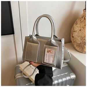 Detailed view of silver metallic bucket bag with dual front pockets and glossy PU texture