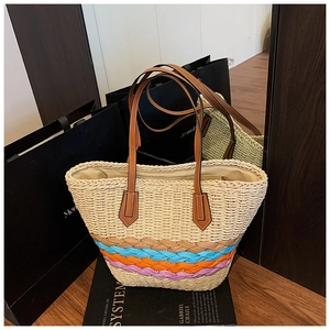 Détail de la base tressée multicolore et des anses en cuir brun sur le sac cabas