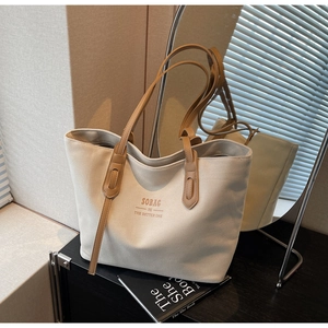 Close-up of canvas tote bag with leather handles on a display shelf with a mirror