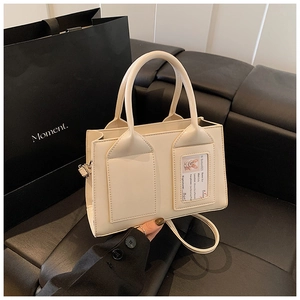 Detail view of cream-white bucket bag featuring a transparent card slot and elegant handles