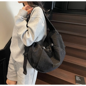 Detail view of black denim crossbody bag with adjustable strap and designer patch