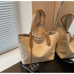 Detail of canvas tote bag with brown leather handles and brand print in soft light