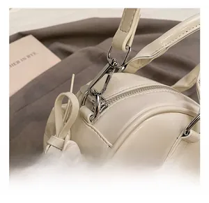 Detail of cream leather boston bag showing metallic hook and decorative ribbon bow