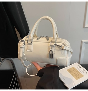 Detailed view of white leather boston bag with top handles and decorative padlock