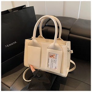 Detail of cream PU leather bucket bag featuring a decorative card window and slim strap