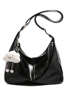 Minimalist black glossy tote bag with white plush cloud charm on a white background