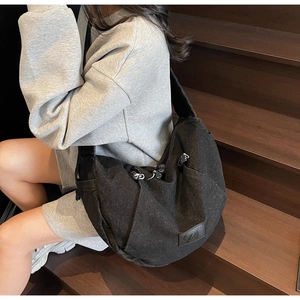 Detail view of the black denim crossbody bag with leather logo patch and metal zipper