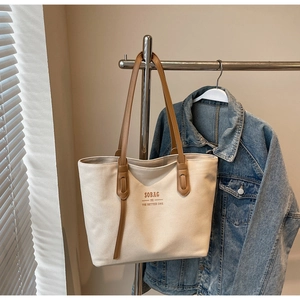 Close-up of canvas tote bag with brown leather handles and SOBAG typography detail