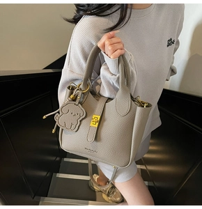 Detail of grey lychee leather bucket bag with gold twist lock and dog charm