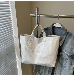 Dettaglio ravvicinato di una borsa tote bianca con trama stropicciata e stampa TOTE BAG