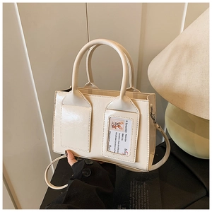Detail of cream bucket bag featuring glossy leather finish and transparent card slot