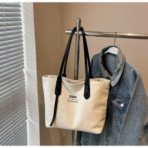 Detail of sturdy cream canvas tote bag with black leather reinforced shoulder straps