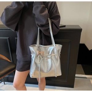 Dettaglio della borsa tote argento in pelle cerata con texture metallica e ciondolo