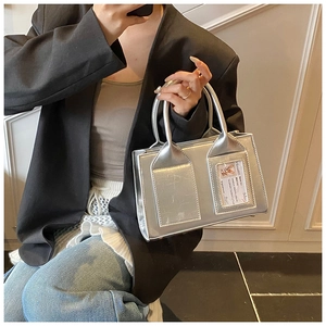 Detail of silver metallic bucket bag with dual handles and decorative card slot