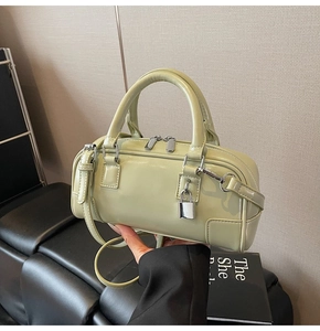 Detail of light green patent leather boston bag with silver padlock and double handles