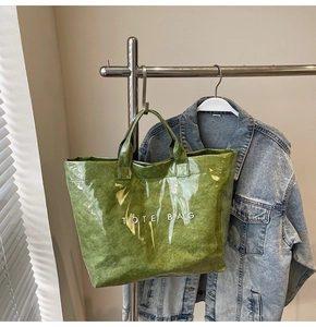 Dettaglio borsa tote verde effetto stropicciato con finitura lucida e testo bianco
