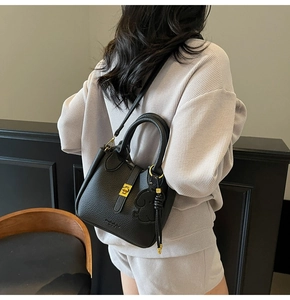 Detail of black lychee grain leather bucket bag with gold hardware and logo embossing