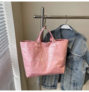 Dettaglio della borsa tote rosa lucida con texture stropicciata e scritte bianche