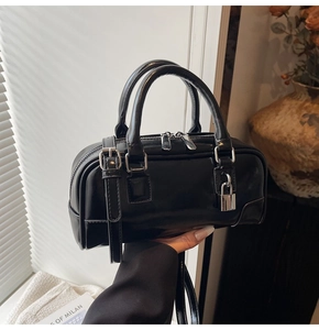 Detail of black glossy leather handbag with silver padlock and metal hardware