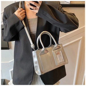 Mini silver metallic bucket bag with dual handles and stylish front pockets on model