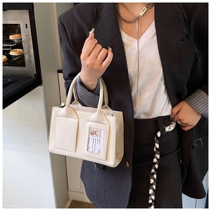 Close-up of cream bucket bag with transparent card slot shown in a lifestyle kitchen setting