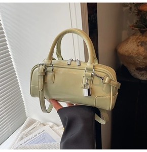Detail of sage green leather bowling bag with silver lock and detachable strap