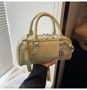 Detail of light green Boston handbag with silver padlock and glossy leather texture