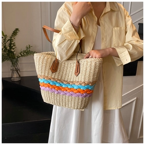 Détail du sac cabas en paille tissé avec accents colorés et poignées en cuir marron